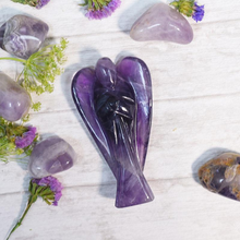 Load image into Gallery viewer, Amethyst Angel figurine placed on a white table with scattered amethyst stones in the background