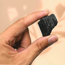 Load image into Gallery viewer, Raw Black Tourmaline crystal placed on the hand representing protection, clarity, and healing energy.