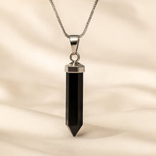 Load image into Gallery viewer, Black Onyx Pencil Pendant displayed fully on white silk cloth to show its natural colour, shape and finish