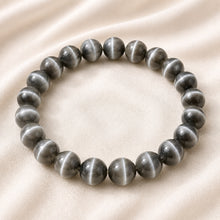 Load image into Gallery viewer, Cat Eye Bracelet displayed fully on white silk cloth to show its natural colour, shape and finish