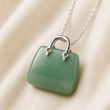 Load image into Gallery viewer, Green Jade Mini Handbag Pendant displayed fully on white silk cloth to show its natural colour, shape and finish