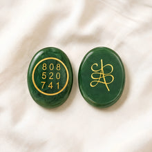 Load image into Gallery viewer, Green Jade Zibu Coin displayed fully on white silk cloth to show its natural colour, shape and finish