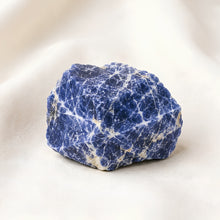 Load image into Gallery viewer, Sodalite Raw Stone displayed fully on white silk cloth to show its natural colour, shape and finish