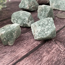 Load image into Gallery viewer, Green Aventurine raw stones arranged on a wooden table symbolizing luck, opportunity, and growth.