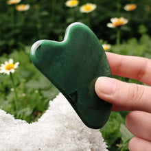 Load image into Gallery viewer, Green Jade Gua Sha face crystal held in hand, promoting cooling, skin renewal, and prosperity benefits.