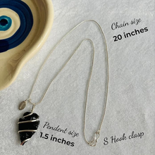 Load image into Gallery viewer, Arrowhead-shaped black obsidian pendant with chain styled with flowers for jewelry display