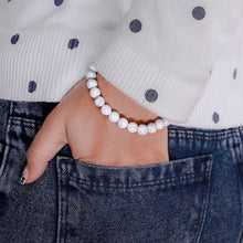 Load image into Gallery viewer, Lifestyle shot of a Howlite bracelet on a person&#39;s wrist, emphasizing comfort and beauty.
