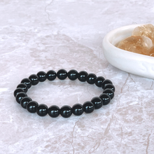Load image into Gallery viewer, The Black Obsidian bracelet with a focus on its vibrant color and unique texture.
