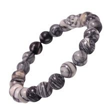 Load image into Gallery viewer, Model wearing a stylish Black Picasso Jasper bracelet to highlight its elegance and aesthetic appeal. Get to know more about the Black Picasso Jasper benefits
