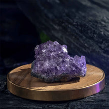 Load image into Gallery viewer, Amethyst raw stone cluster placed on a wooden table, symbolizing calm, insight, and protection.
