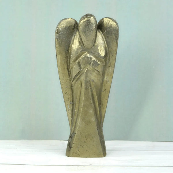 Angel figurine placed on a white table in a minimal decorative setting.