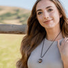 A woman wearing a black onyx crystal pendant wrapped in silver wire during an outdoor photoshoot.
