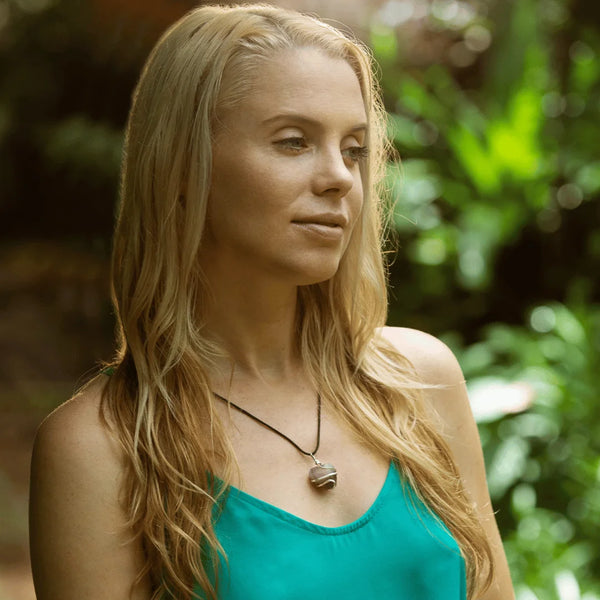 Woman wearing a handcrafted black onyx pendant necklace with long hair, photographed outdoors.