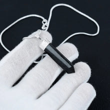 Load image into Gallery viewer, Black Tourmaline pencil necklace laid across a relaxed palm, photographed top-down with clear detail and soft shadows.
