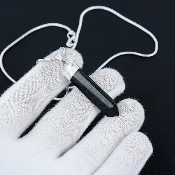 Black Tourmaline pencil necklace laid across a relaxed palm, photographed top-down with clear detail and soft shadows.