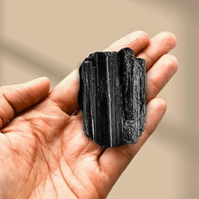 Load image into Gallery viewer, Black Tourmaline raw stone resting on the hand, symbolizing clarity, healing, and personal growth
