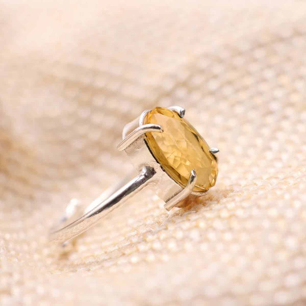 Close-up of Citrine diamond cut oval ring on a textured fabric surface, symbolizing success, prosperity and positive energy.
