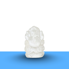 Clear quartz Ganesh figurine on a minimalist white and blue background, showing polished details and elegant design