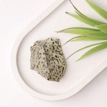 Load image into Gallery viewer, Dalmatian Jasper raw stone placed on a white table, symbolizing joy, stability, and grounding.
