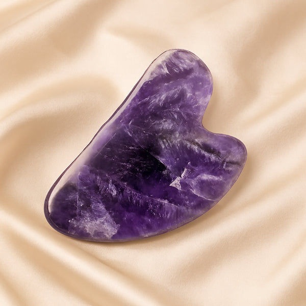 Amethyst Gua Sha displayed fully on white silk cloth to show its natural colour, shape and finish