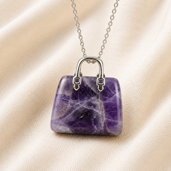Amethyst Mini Handbag Pendant displayed fully on white silk cloth to show its natural colour, shape and finish