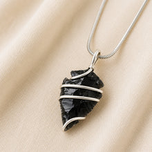 Load image into Gallery viewer, Black Obsidian Arrowhead Pendant displayed fully on white silk cloth to show its natural colour, shape and finish
