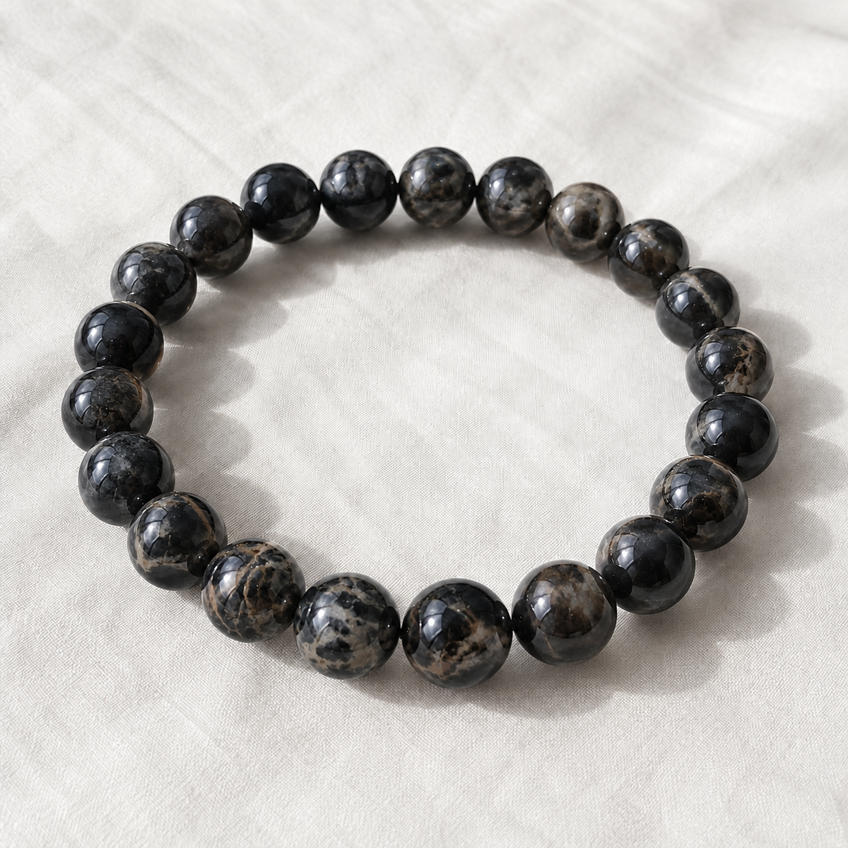 Black Picasso Jasper Bracelet displayed fully on white silk cloth to show its natural colour, shape and finish