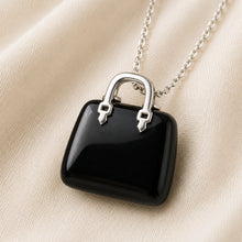 Load image into Gallery viewer, Black Tourmaline Mini Handbag Pendant displayed fully on white silk cloth to show its natural colour, shape and finish
