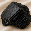 Close-up of authentic natural Black Tourmaline showing crystal texture, colour and craftsmanship – black tourmaline raw stone symbol of protection grounding and