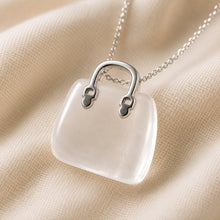 Load image into Gallery viewer, Clear Quartz Mini Handbag Pendant displayed fully on white silk cloth to show its natural colour, shape and finish
