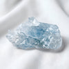 Clear Quartz Raw Stone displayed fully on white silk cloth to show its natural colour, shape and finish