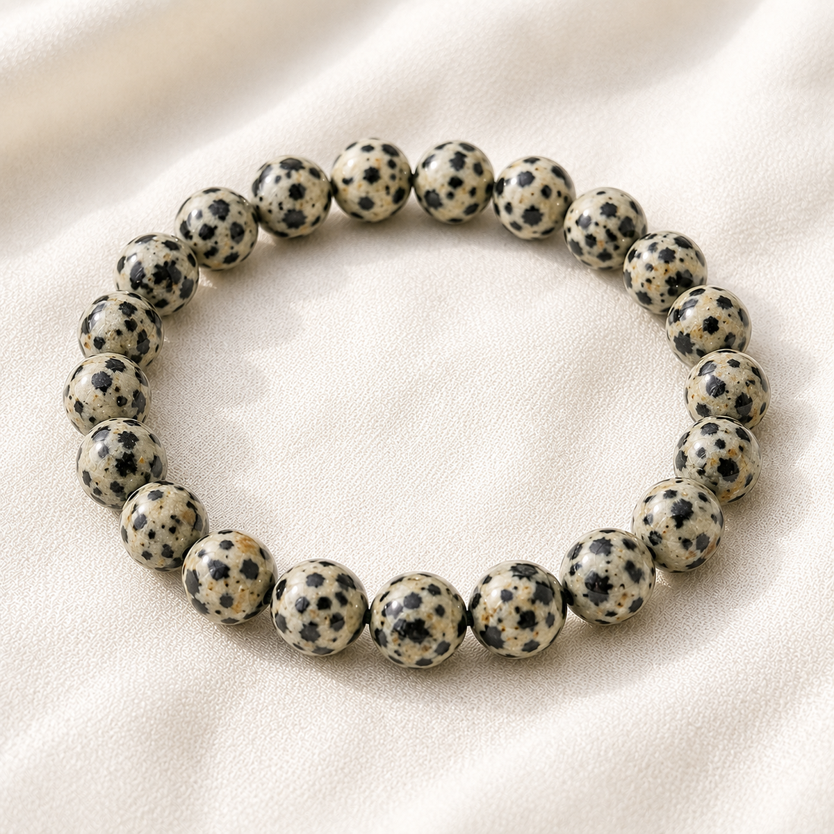Dalmatian Jasper Bracelet displayed fully on white silk cloth to show its natural colour, shape and finish