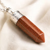 Goldstone Pencil Pendant displayed fully on white silk cloth to show its natural colour, shape and finish