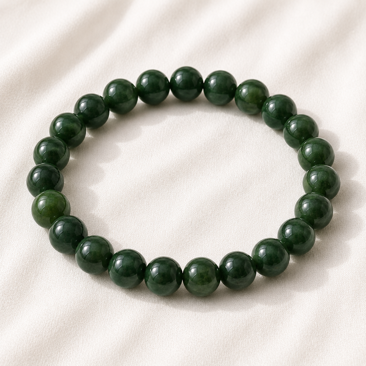 Green Jade Bracelet displayed fully on white silk cloth to show its natural colour, shape and finish