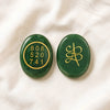 Green Jade Zibu Coin displayed fully on white silk cloth to show its natural colour, shape and finish
