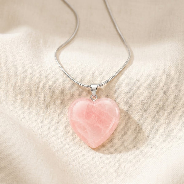 Rose Quartz Heart Pendant displayed fully on white silk cloth to show its natural colour, shape and finish