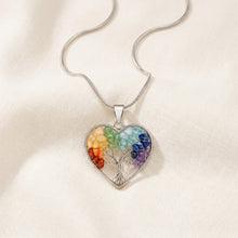 Load image into Gallery viewer, 7 Chakra Heart Pendant displayed fully on white silk cloth to show its natural colour, shape and finish
