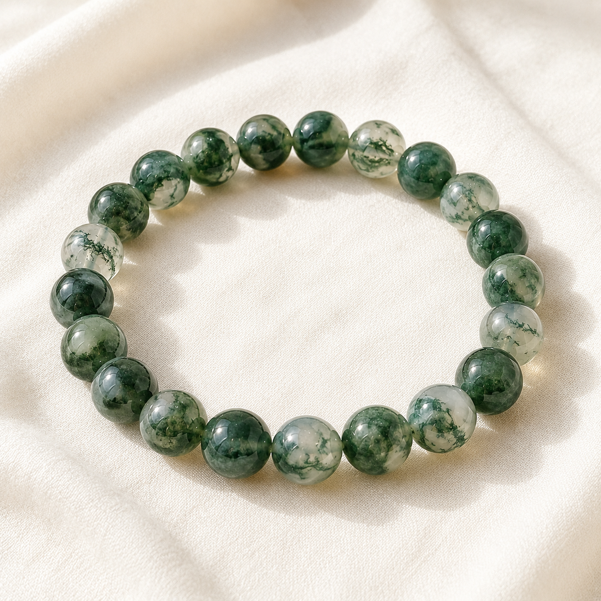 Moss Agate Bracelet displayed fully on white silk cloth to show its natural colour, shape and finish