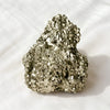 Pyrite Raw Stone displayed fully on white silk cloth to show its natural colour, shape and finish
