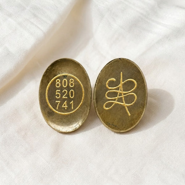 Pyrite Zibu Coin displayed fully on white silk cloth to show its natural colour, shape and finish