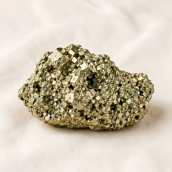 Raw Pyrite Raw Stone displayed fully on white silk cloth to show its natural colour, shape and finish