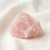 Raw Rose Quartz Raw Stone displayed fully on white silk cloth to show its natural colour, shape and finish