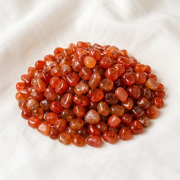 Red Carnelian Chips displayed fully on white silk cloth to show its natural colour, shape and finish