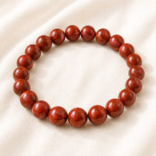 Load image into Gallery viewer, Red Jasper Bracelet displayed fully on white silk cloth to show its natural colour, shape and finish
