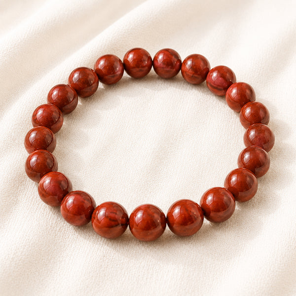 Red Jasper Bracelet displayed fully on white silk cloth to show its natural colour, shape and finish
