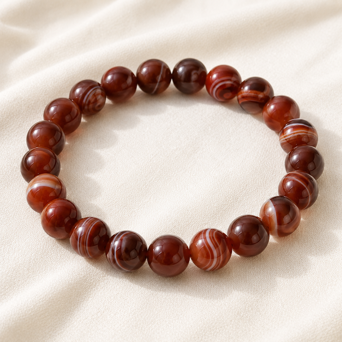 Red Sulemani Hakik Bracelet displayed fully on white silk cloth to show its natural colour, shape and finish