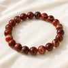 Red Sulemani Hakik Bracelet displayed fully on white silk cloth to show its natural colour, shape and finish