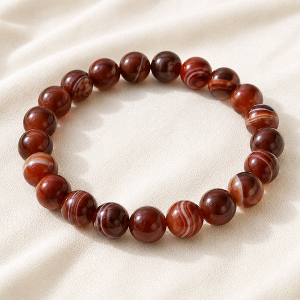Red Sulemani Hakik Bracelet displayed fully on white silk cloth to show its natural colour, shape and finish