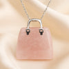 Rose Quartz Mini Handbag Pendant displayed fully on white silk cloth to show its natural colour, shape and finish