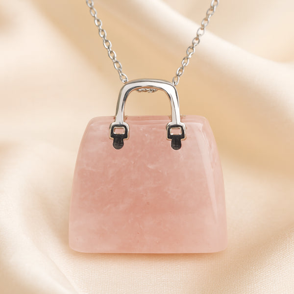 Rose Quartz Mini Handbag Pendant displayed fully on white silk cloth to show its natural colour, shape and finish